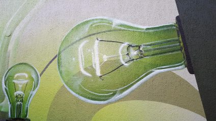 Rinnovabili • Artistic mural of green light bulbs representing the global energy transition and rising electricity demand projected in BloombergNEF's New-Energy-Outlook 2025.